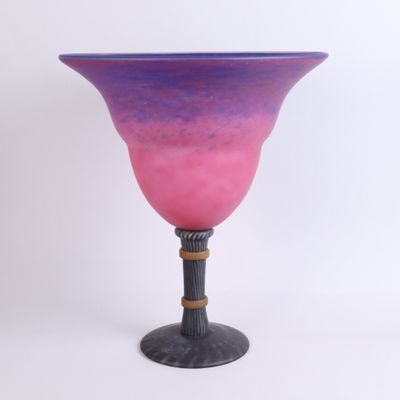 pink and purple glass vase on black stand against a white background