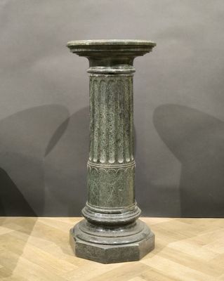 a green vase sitting on top of a wooden table