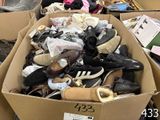 plusieurs paires de chaussures dans une boîte en carton posée sur le sol
