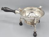 a silverplated bowl with black handles and a wooden handle