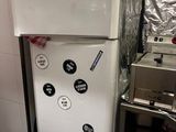 un réfrigérateur blanc dans une cuisine, à côté d'une cuisinière