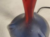 a red vase with a blue base on a white table