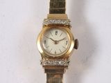 a gold watch with diamonds on it sitting on a white surface