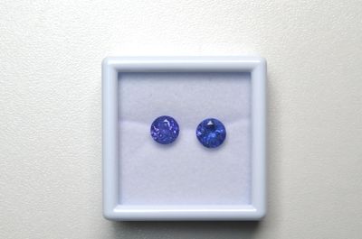 une paire de saphirs bleus dans un écrin blanc posé sur une surface blanche