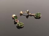 a pair of green and gold earrings on a black surface