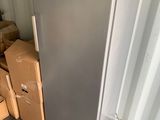 un réfrigérateur argenté au milieu d'une pile de cartons