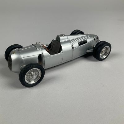 a silver model of a racing car on a white surface