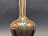 a green and brown vase sitting on a table