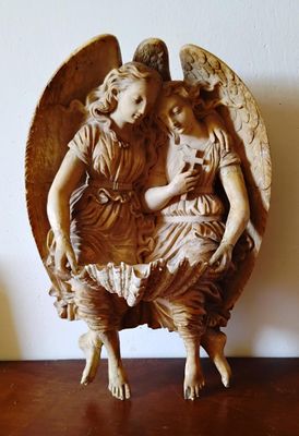 une statue représentant un ange tenant un enfant dans ses bras, posée sur une table