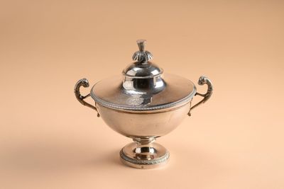 un bol ancien en métal argenté avec couvercle, sur fond beige