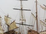 three wooden model ships sitting on top of each other on a white surface