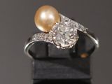 une bague de fiançailles ornée d'une perle et de diamants sur un fond noir