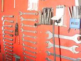 a red wall with a bunch of tools hanging on it