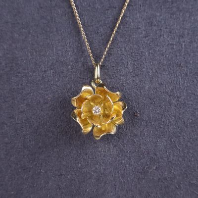 a close up of a necklace with a flower on it