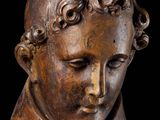 an old wooden statue of a young boy with curly hair