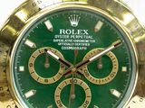 a gold and green rolex watch on a white background