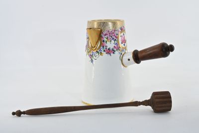 a white vase with a wooden handle next to a wooden spoon