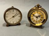 two clocks sitting next to each other on a table