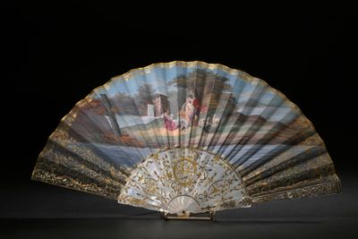 un éventail avec un tableau posé sur une table