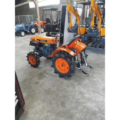 un tracteur orange garé dans un entrepôt, avec d'autres tracteurs en arrière-plan