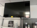 une télévision à écran plat accrochée au mur au-dessus d'une étagère