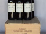 quatre bouteilles de vin se trouvent dans une caisse en bois posée sur une table