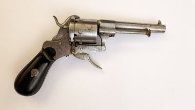 un gros plan d'un revolver posé sur une surface blanche, avec une crosse noire