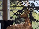 une statue de cerf posée sur une table devant une fenêtre