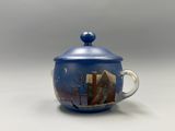 une tasse bleue avec un couvercle sur lequel est représentée une ville