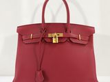 un sac à main en cuir rouge muni d'un fermoir doré sur la poignée