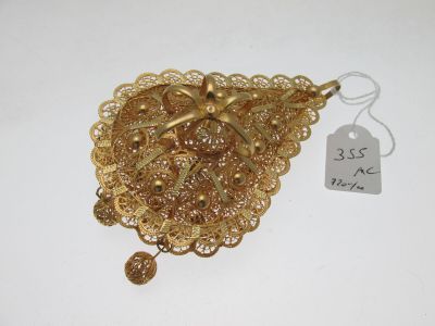 une broche en or posée sur un fond blanc, avec une étiquette de prix