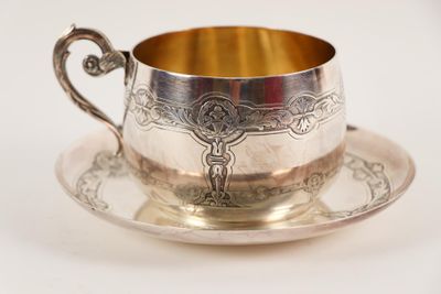 une tasse et une soucoupe en argent posées sur une soucoupe