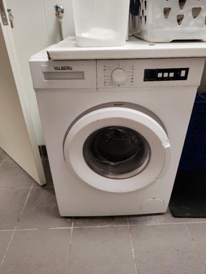 une machine à laver blanche posée dans un coin de la cuisine