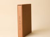 un livre brun posé sur une table à côté d'un mur blanc