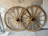 two old wooden wagon wheels leaning against a wall