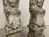 two stone statues of a lion and a lion cub on a pedestal