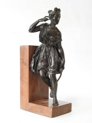 bronze statue of a woman with a bow on a wooden base
