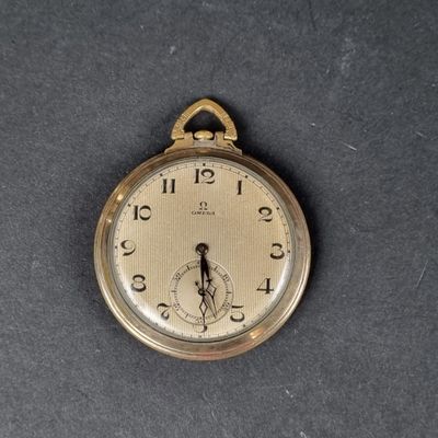 une montre de poche en or posée sur une table, sur fond noir