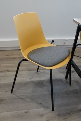 a yellow chair sitting next to a desk with a laptop on it
