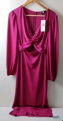 robe rose à manches longues sur un cintre, devant un mur blanc