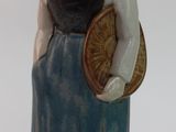 une figurine en céramique représentant une femme portant un panier sur l'épaule