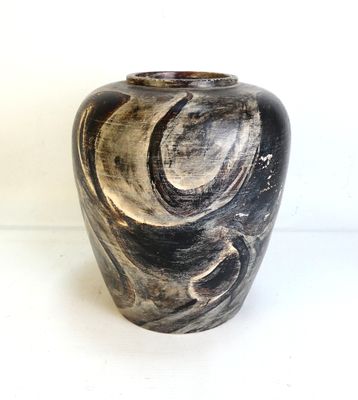 un vase noir et blanc posé sur une surface blanche