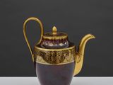 une image représentant une théière violette et dorée posée sur une table blanche