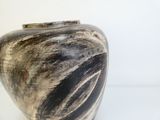 un vase noir et blanc posé sur une surface blanche