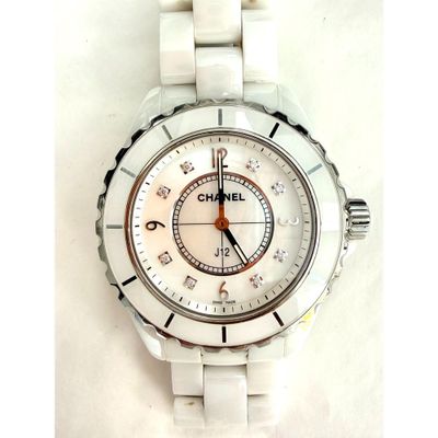 une montre en céramique blanche avec un cadran blanc posée sur une surface blanche
