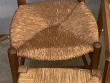 a wooden chair with a woven seat next to a small stool