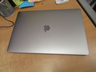 un ordinateur portable Apple argenté posé sur un bureau en bois