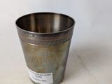 an old silver cup sitting on top of a white table