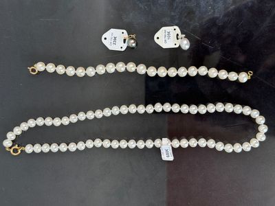 un collier de perles et des boucles d'oreilles ornées de breloques en forme de dés, exposés dans une vitrine