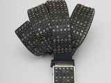 La ceinture est en cuir noir et est dotée d'une boucle métallique.